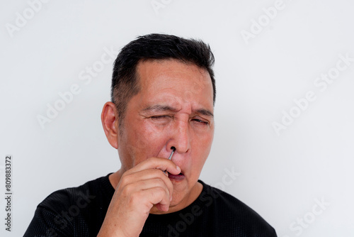 Middle-aged Asian man with low pain tolerance, reacting in pain after accidentally cutting the tip of his index finger, isolated on white background