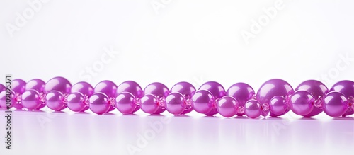 A copy space image featuring purple pink beads placed against a pristine white backdrop