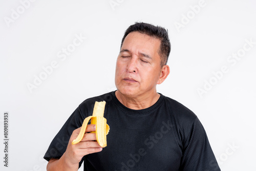 A middle-aged Asian man savoring the sweet taste of a ripe lakatan banana. Isolated on a white background. photo