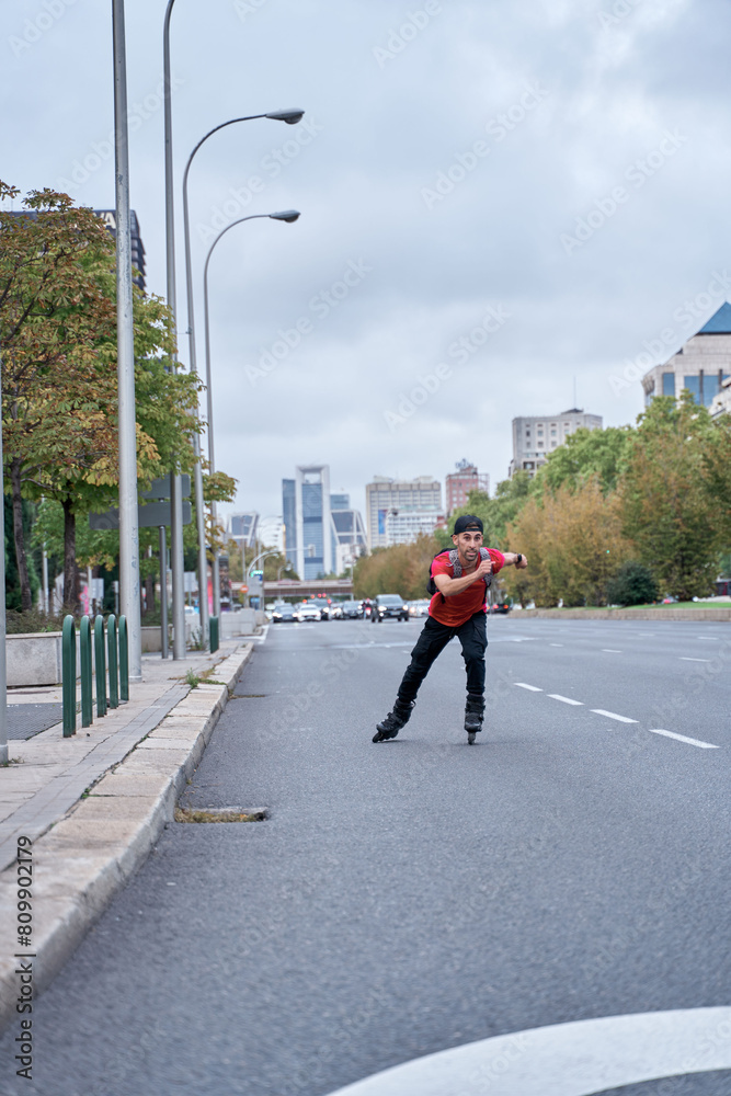Young man on roller skates riding outdoors on urban street. Smiling man rollerblading on sunny day Young man on roller skates riding outdoors on urban street. Smiling man rollerblading on sunny day