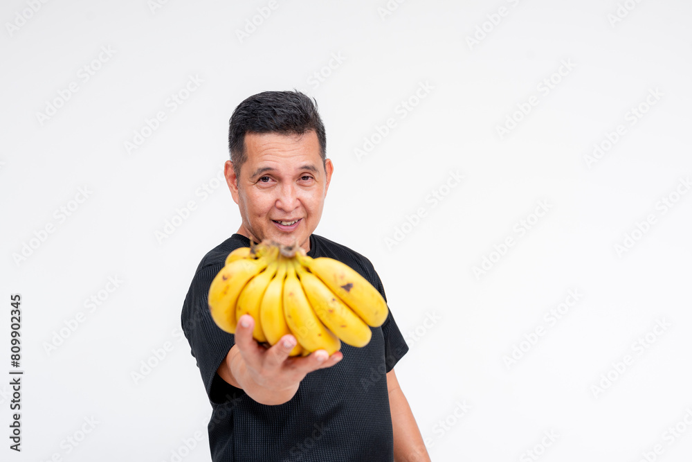 Smiling middle-aged Asian man offering a bunch of bananas, isolated on white Smiling middle-aged Asian man offering a bunch of bananas, isolated on white