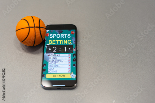 smartphone with application for sport bets and a basketball ball, concept of online bets  photo