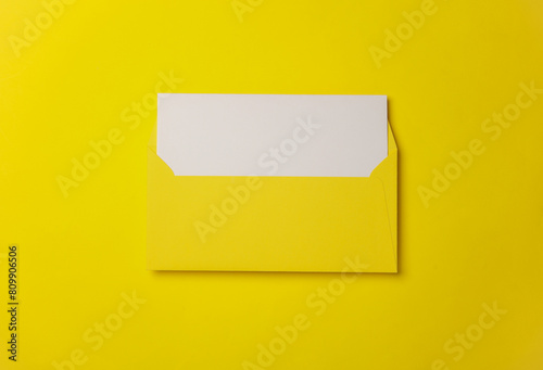 Yellow envelope with white blank letter on a yelllow background. Creative layout photo