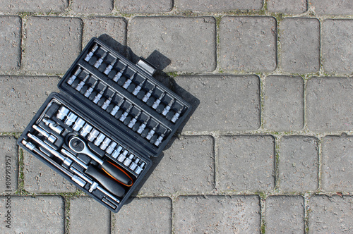 A set of repairing tools in a plastic case on a concrete paving slabs 
