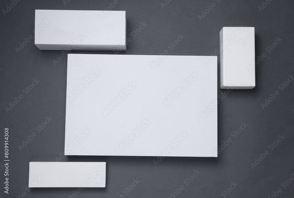 Different shapes of white cardboard boxes for presentation products on dark gray background. Mockup for design. Top view Different shapes of white cardboard boxes for presentation products on dark gray background. Mockup for design. Top view