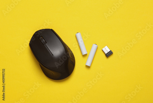 Wireless PC mouse with USB flash drive and batteries on a yellow background