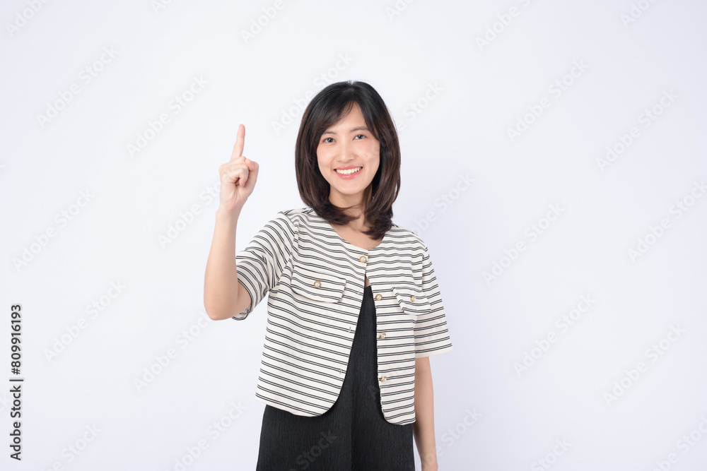 A Young asian woman pointing finger to free copy space isolated on white studio background A Young asian woman pointing finger to free copy space isolated on white studio background