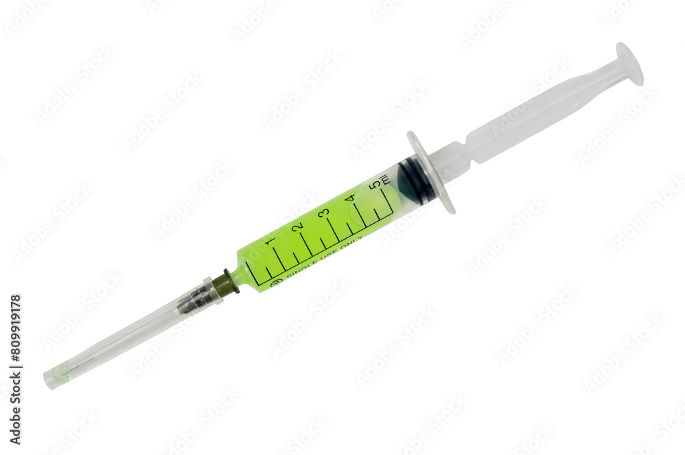 A syringe with a green liquid in it. The syringe is long and thin A syringe with a green liquid in it. The syringe is long and thin