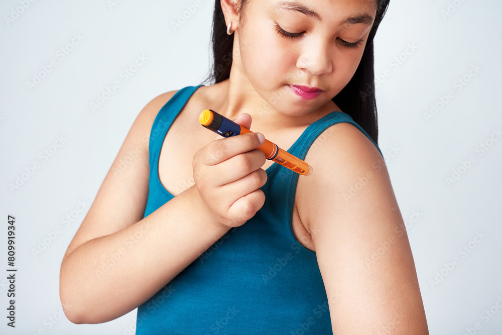 Medicine, girl and insulin shot in studio for blood sugar levels, glucose or energy for body. Young person, child and injection for wellness in white background, diabetes or medical treatment for kid Medicine, girl and insulin shot in studio for blood sugar levels, glucose or energy for body. Young person, child and injection for wellness in white background, diabetes or medical treatment for kid