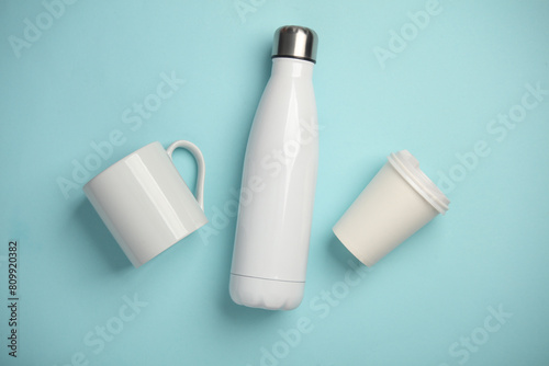 Mockup of white empty ceramic and cardboard cup and thermos bottle on blue pink blue background photo