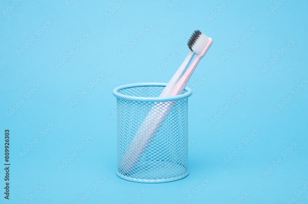 Two toothbrushes in a basket on a blue background Two toothbrushes in a basket on a blue background
