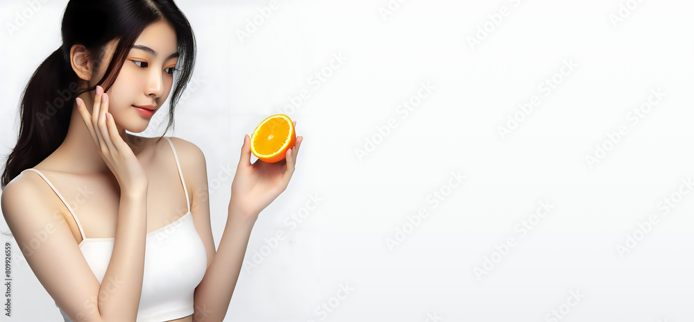 Portrait of Asian girl with shining clean skin of face holding orange halves in isolated on white background. face care concept Portrait of Asian girl with shining clean skin of face holding orange halves in isolated on white background. face care concept