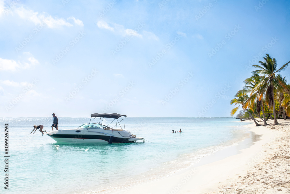 People enjoying themselves in a small boat floating in the ocean near a beach. The scene is calm, relaxing and fun. Concept of tourism, enjoyment, summer and relaxation.