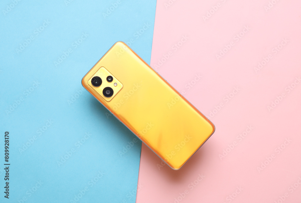 Back side of yellow modern smartphone on pink blue background Back side of yellow modern smartphone on pink blue background