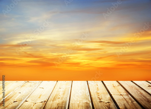 Wooden table on sky background and sunset light