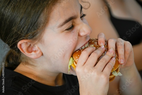 High resolution image close up portrait of a young girl enjoying her cheese burger- Israel
