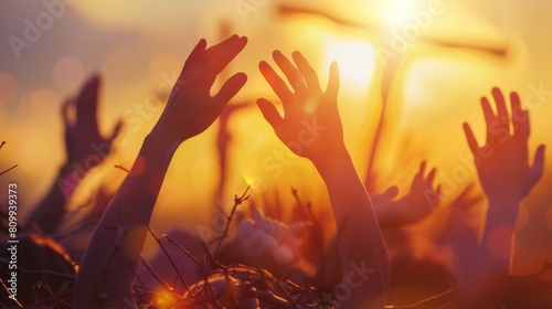 People raising their hands in worship with a bright light in the background. photo