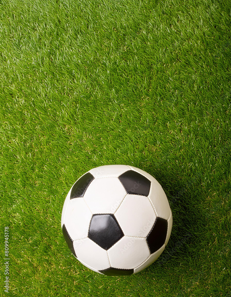 A soccer ball on a green grass field, top view, copyspace on a side