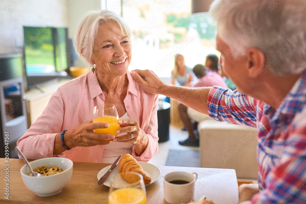 Grandparents Eating Breakfast Together With Three Generation Family In Background Grandparents Eating Breakfast Together With Three Generation Family In Background