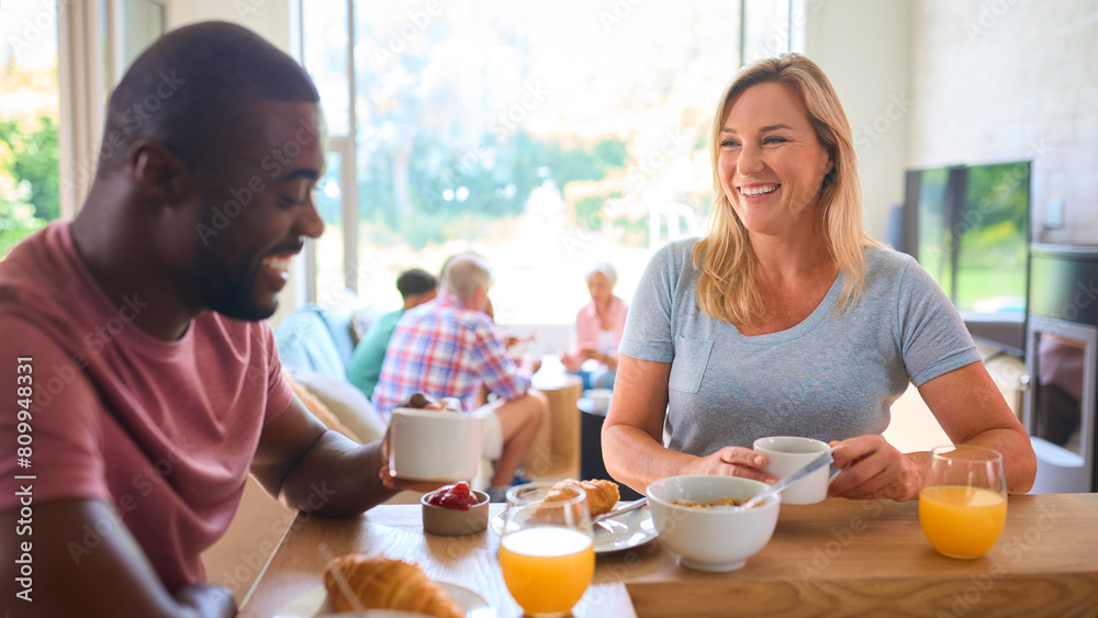 Parents Eating Breakfast Together With Three Generation Family In Background