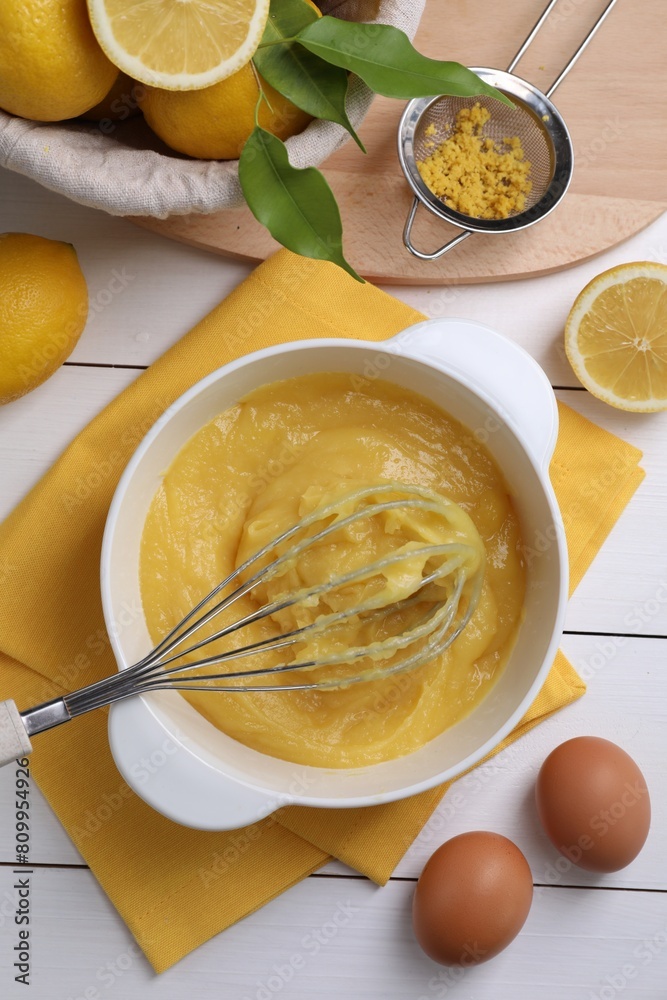 Delicious lemon curd in bowl, ingredients, whisk and sieve on white wooden table, flat lay Delicious lemon curd in bowl, ingredients, whisk and sieve on white wooden table, flat lay
