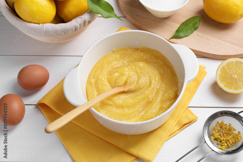 Delicious lemon curd in bowl, ingredients, spoon and sieve on white wooden table, above view Delicious lemon curd in bowl, ingredients, spoon and sieve on white wooden table, above view