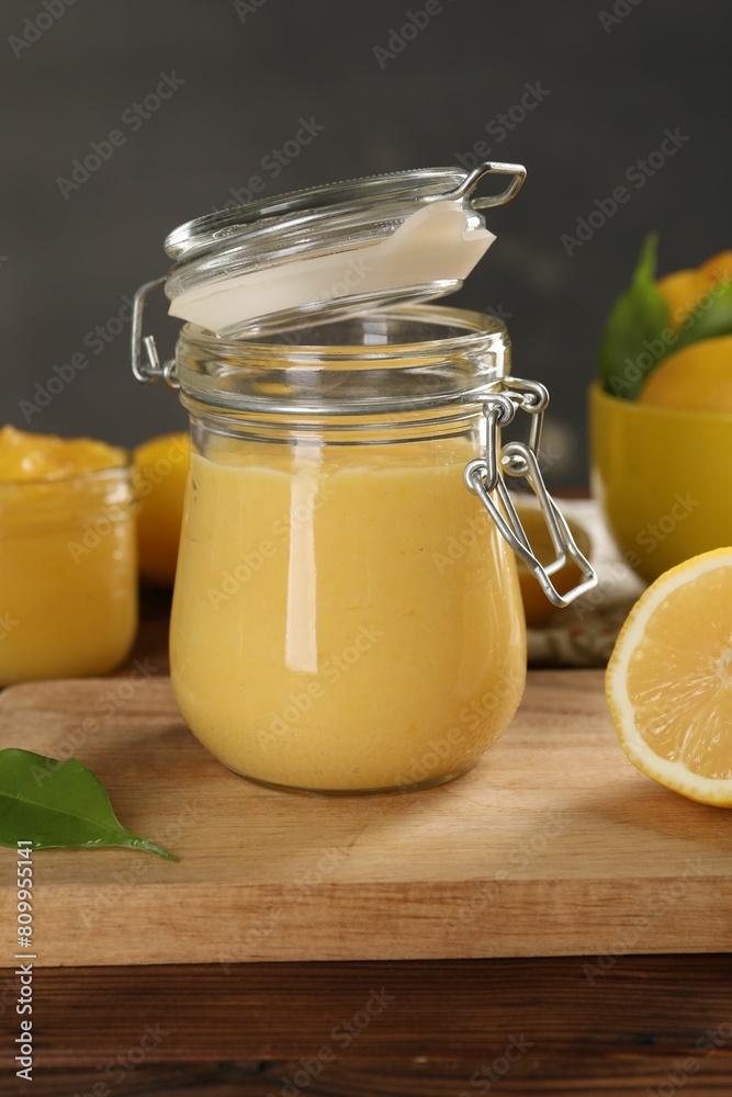 Delicious lemon curd in glass jars, fresh citrus fruit and green leaf on wooden table Delicious lemon curd in glass jars, fresh citrus fruit and green leaf on wooden table