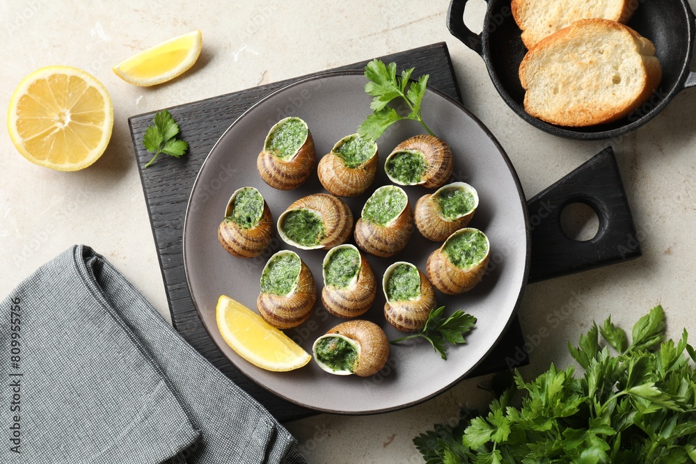 Delicious cooked snails served on light table, flat lay Delicious cooked snails served on light table, flat lay