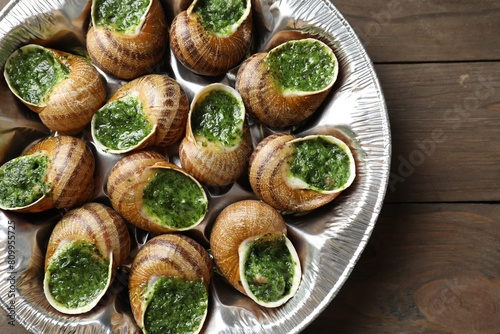 Delicious cooked snails on wooden table, top view