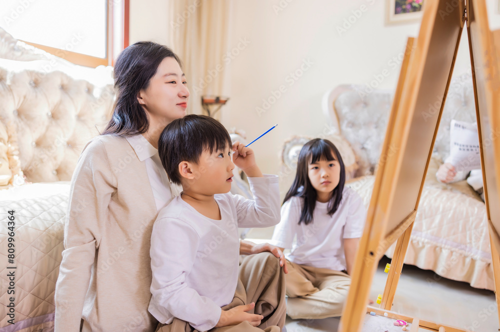 In the living room, the young mother accompanied the two siblings to play games In the living room, the young mother accompanied the two siblings to play games