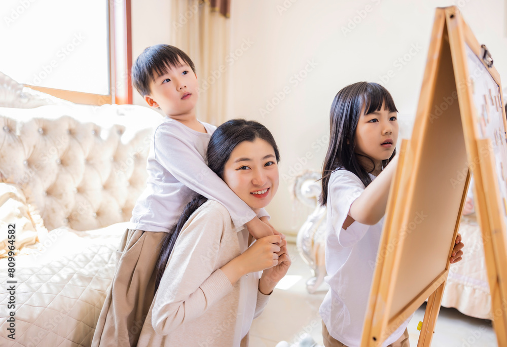 In the living room, the young mother accompanied the two siblings to play games In the living room, the young mother accompanied the two siblings to play games
