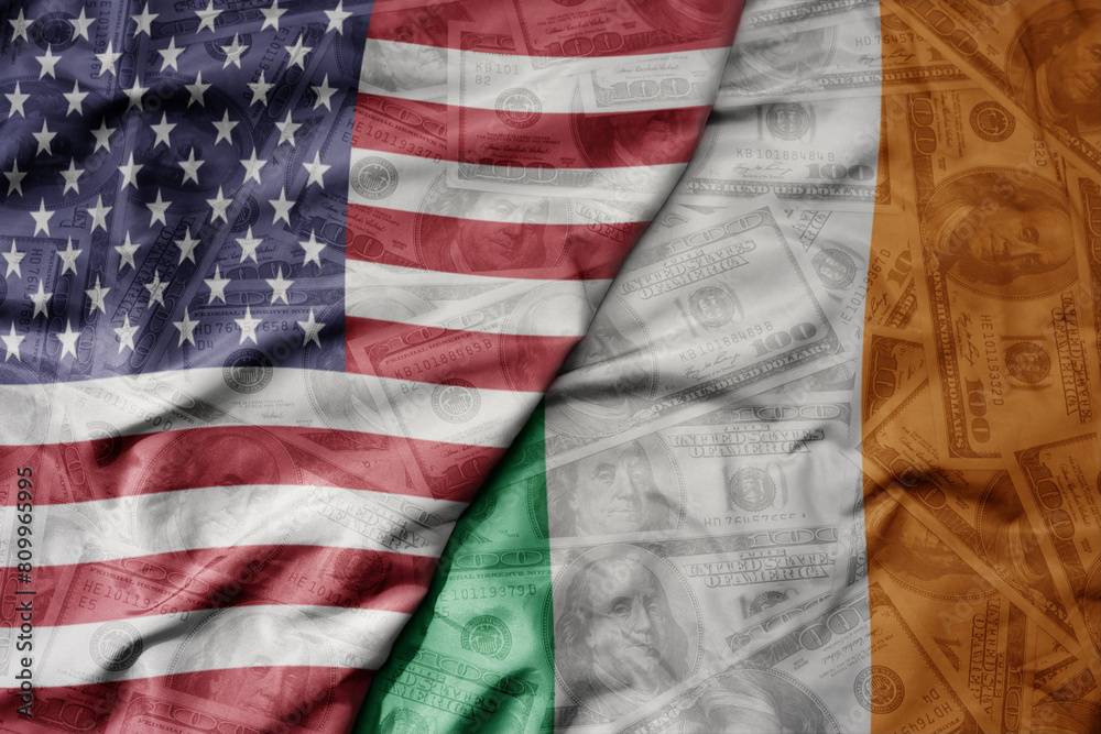 Obraz premium big waving colorful flag of united states of america and national flag of ireland on the dollar money background. finance concept.