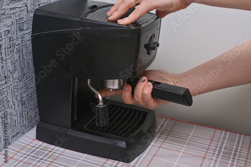 a woman's hand puts ground coffee in the coffee machine photo