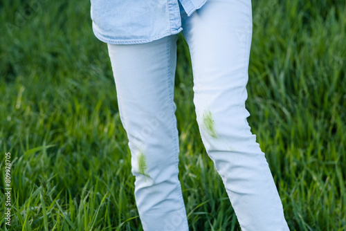 Close up dirty grass stains on white clothes. An unrecognizable person with green knees on a green background.