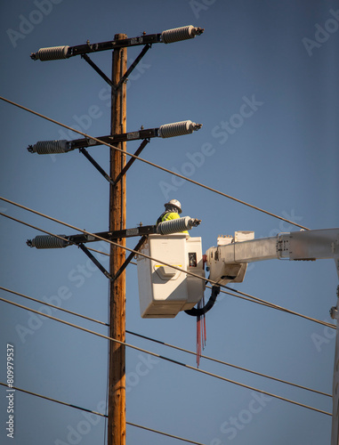 A Man on a manlift working on high electrcity lines on a transmission pole photo