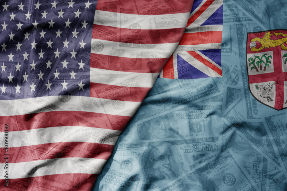 big waving colorful flag of united states of america and national flag of Fiji on the dollar money background. finance concept. big waving colorful flag of united states of america and national flag of Fiji on the dollar money background. finance concept.