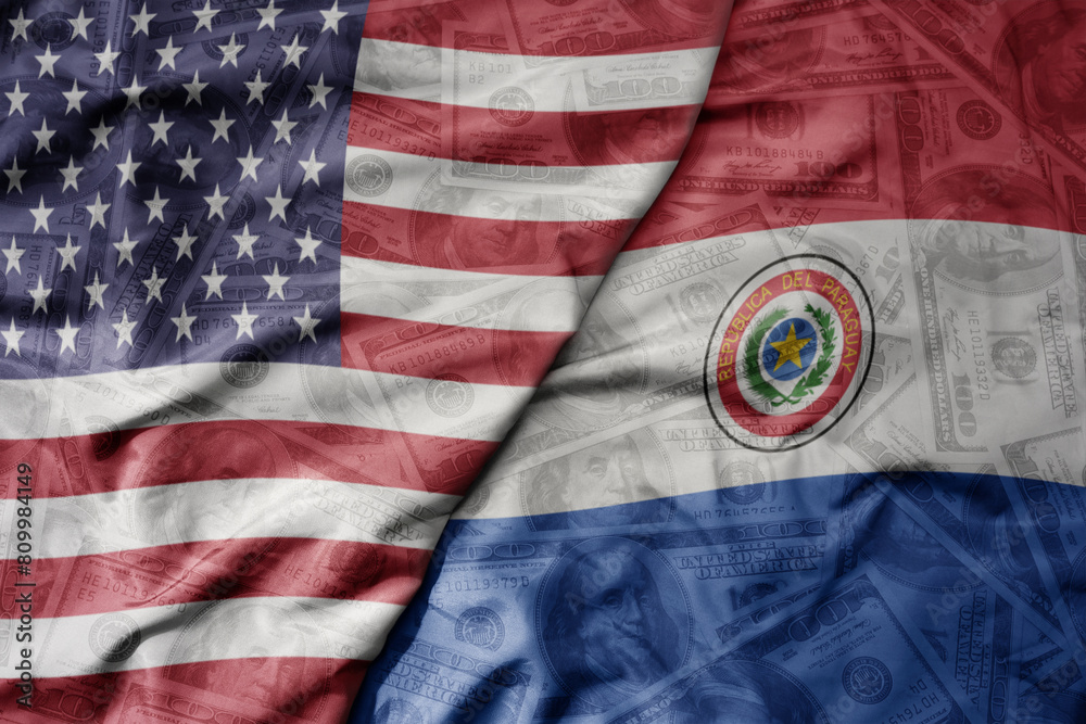 Obraz premium big waving colorful flag of united states of america and national flag of paraguay on the dollar money background. finance concept.