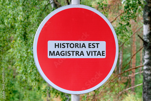 Historia est vitae magistra (History is the tutor of life) Latin phrase on the road sign in front of the forest photo