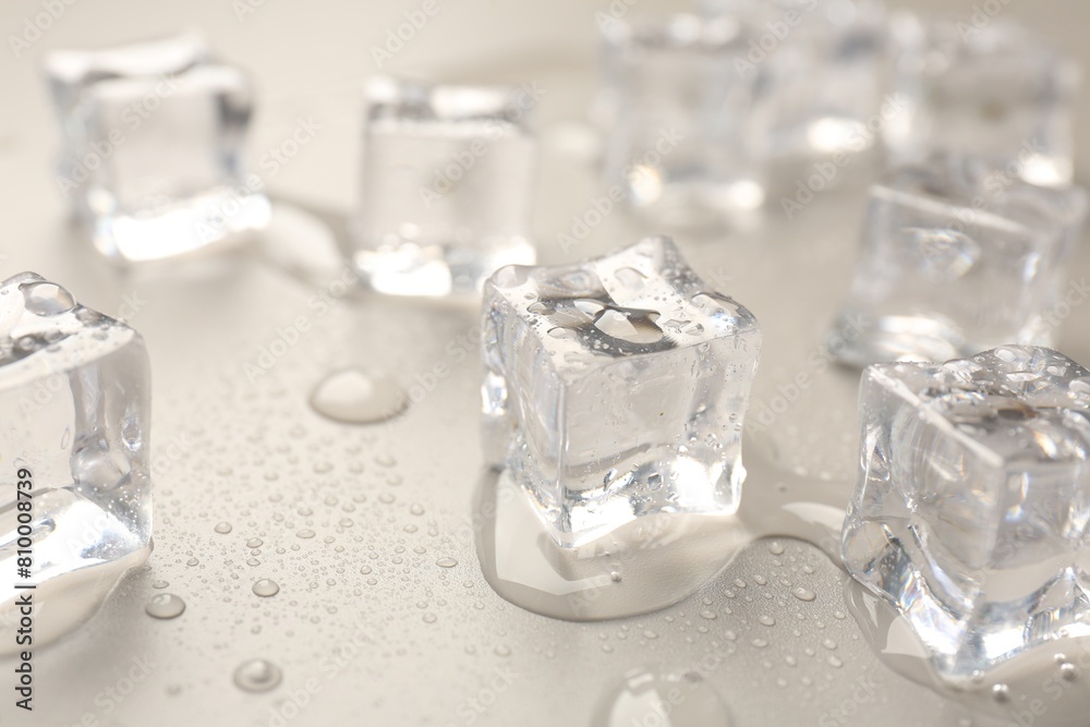 Melting ice cubes and water drops on light grey background, closeup Melting ice cubes and water drops on light grey background, closeup