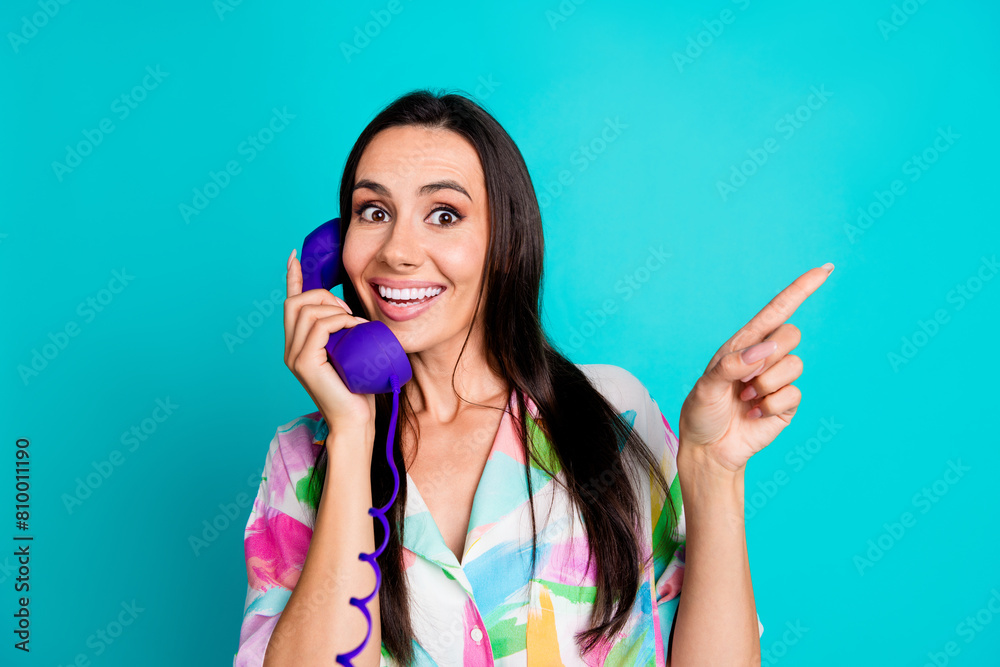 Photo of surprised cheerful woman telephonist wear stylish print clothes recommend banner empty space isolated on cyan color background Photo of surprised cheerful woman telephonist wear stylish print clothes recommend banner empty space isolated on cyan color background