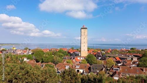 Aerial drone film of the town of west Terschelling with iconic landmark, brick lighthouse brandaris with historic town under blue summer skies photo