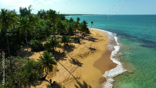 Aerial drone footage moving down the beach at Playa Pinones, Puerto Rico, with people enjoying the afternoon.
