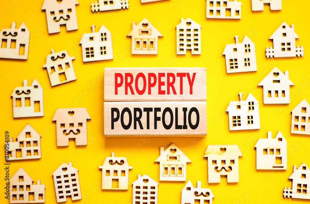 Property portfolio symbol. Concept words Property portfolio on beautiful wooden blocks. Wooden model of houses. Beautiful yellow background. Business Property portfolio concept. Copy space.