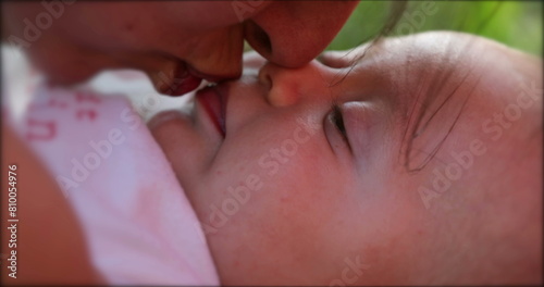 Mother kissing newborn baby infant outdoors photo