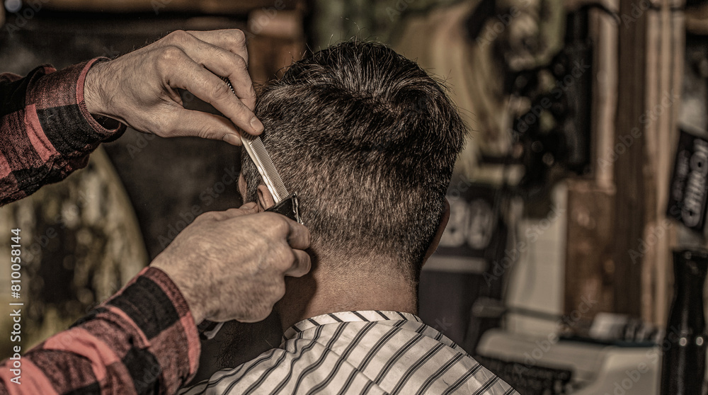 Close up of a professional barber working giving a haircut to a man. Hipster client getting haircut. Hands of barber with hair clipper, close up. Haircut concept
