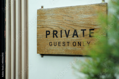 The wooden signboard with the words Private Guest Only hanging on the white wall