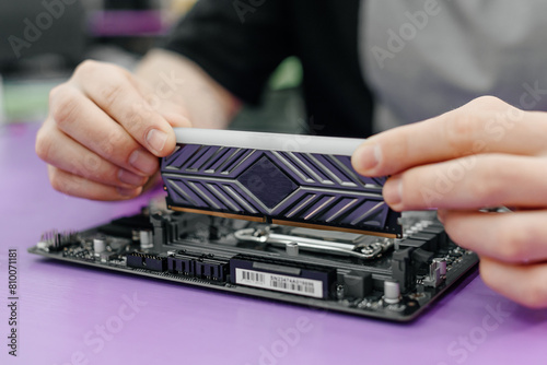 system administrator installing random access memory into motherboard, assembling PC of different accessories or components, close-up view of hands, computer repair and maintenance concept © Anton Pentegov