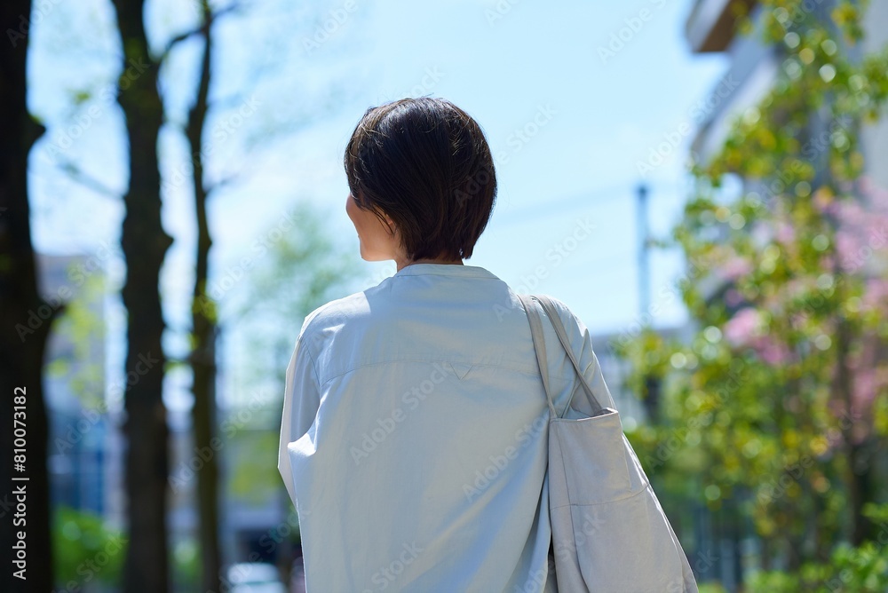 ショッピングバッグを持って街を歩く女性の後ろ姿 ショッピングバッグを持って街を歩く女性の後ろ姿