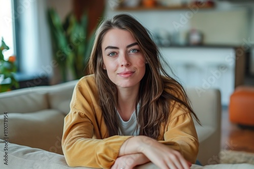 A young Caucasian woman, Irene Montero, sitting on the top of a couch in a living room. photo