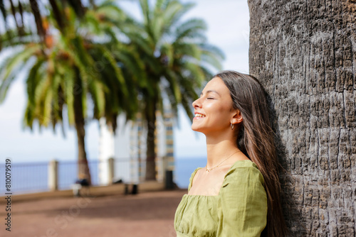 Young woman enjoying sunny day outdoors with palm trees in background